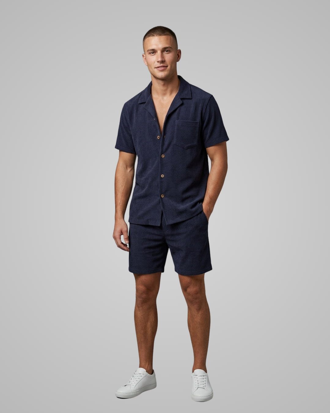 Man wearing a navy blue shirt and shorts set on a gray background