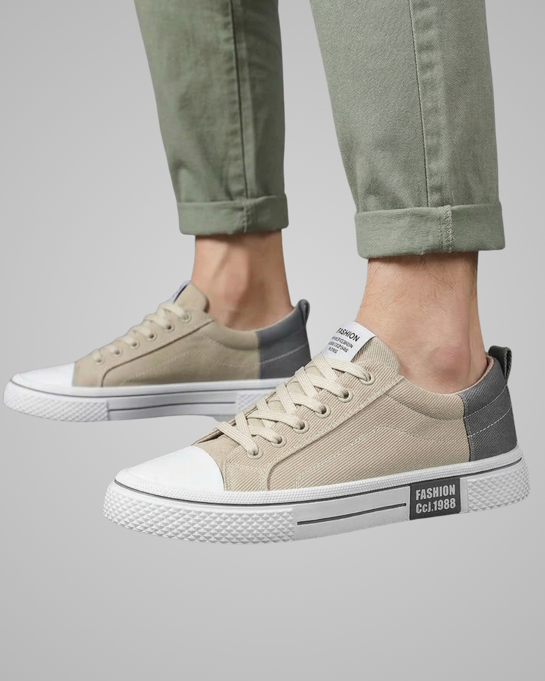 Beige and gray sneakers worn with green pants on a gray background