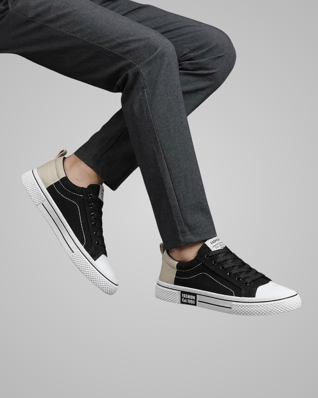 Person wearing black and white sneakers with gray pants on a light gray background