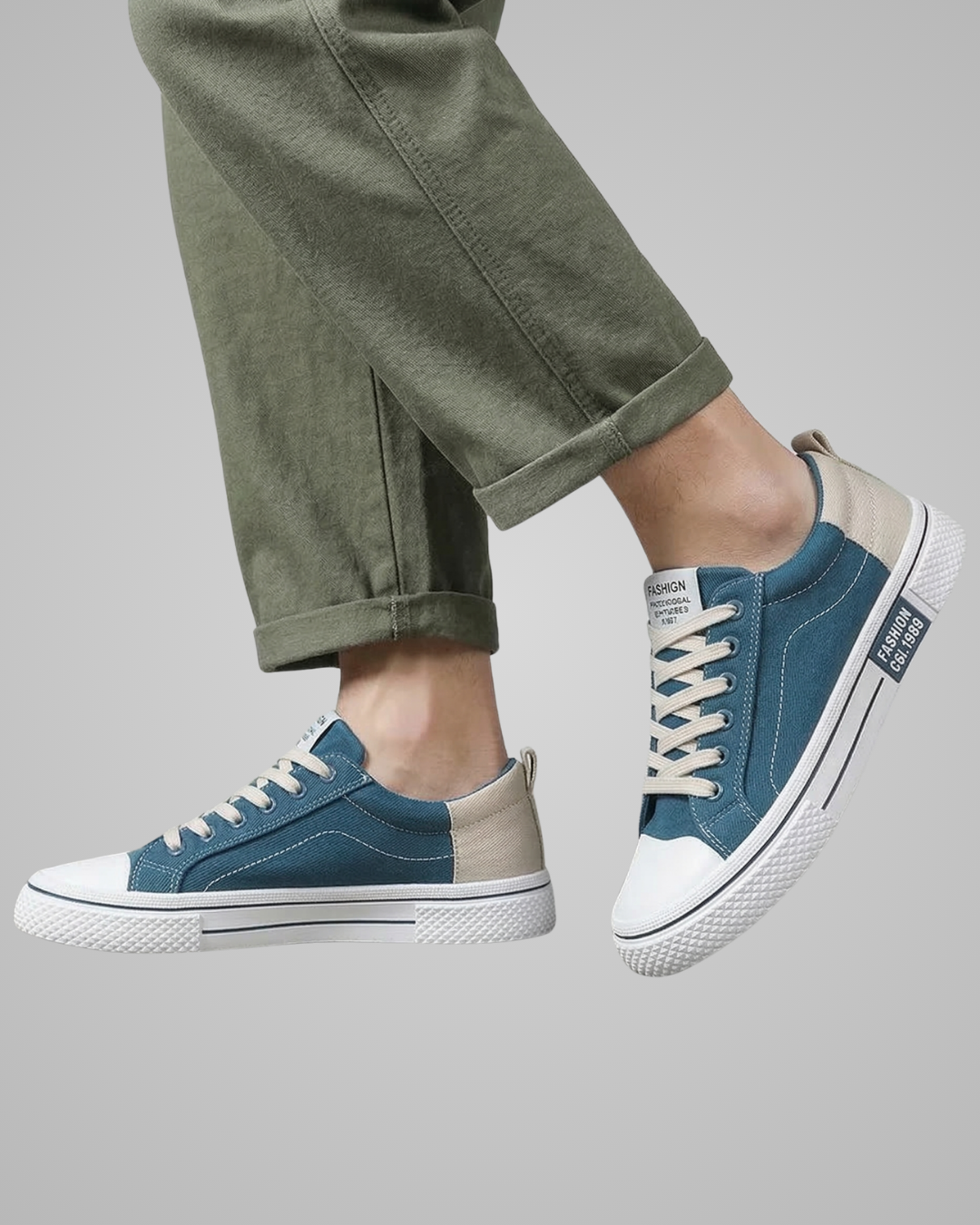 Blue and beige sneakers worn with green pants on a gray background