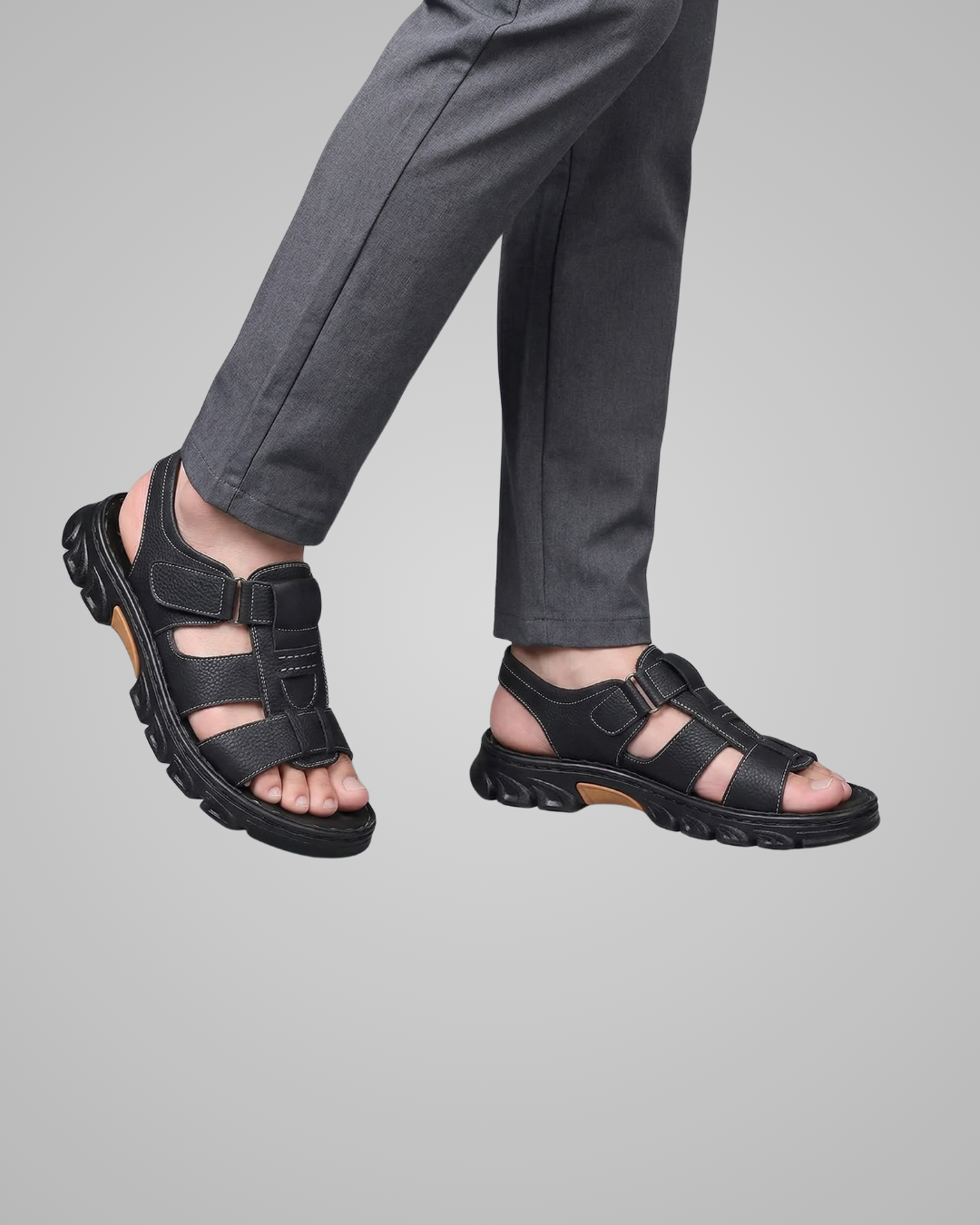 Black sandals worn with gray pants on a gray background