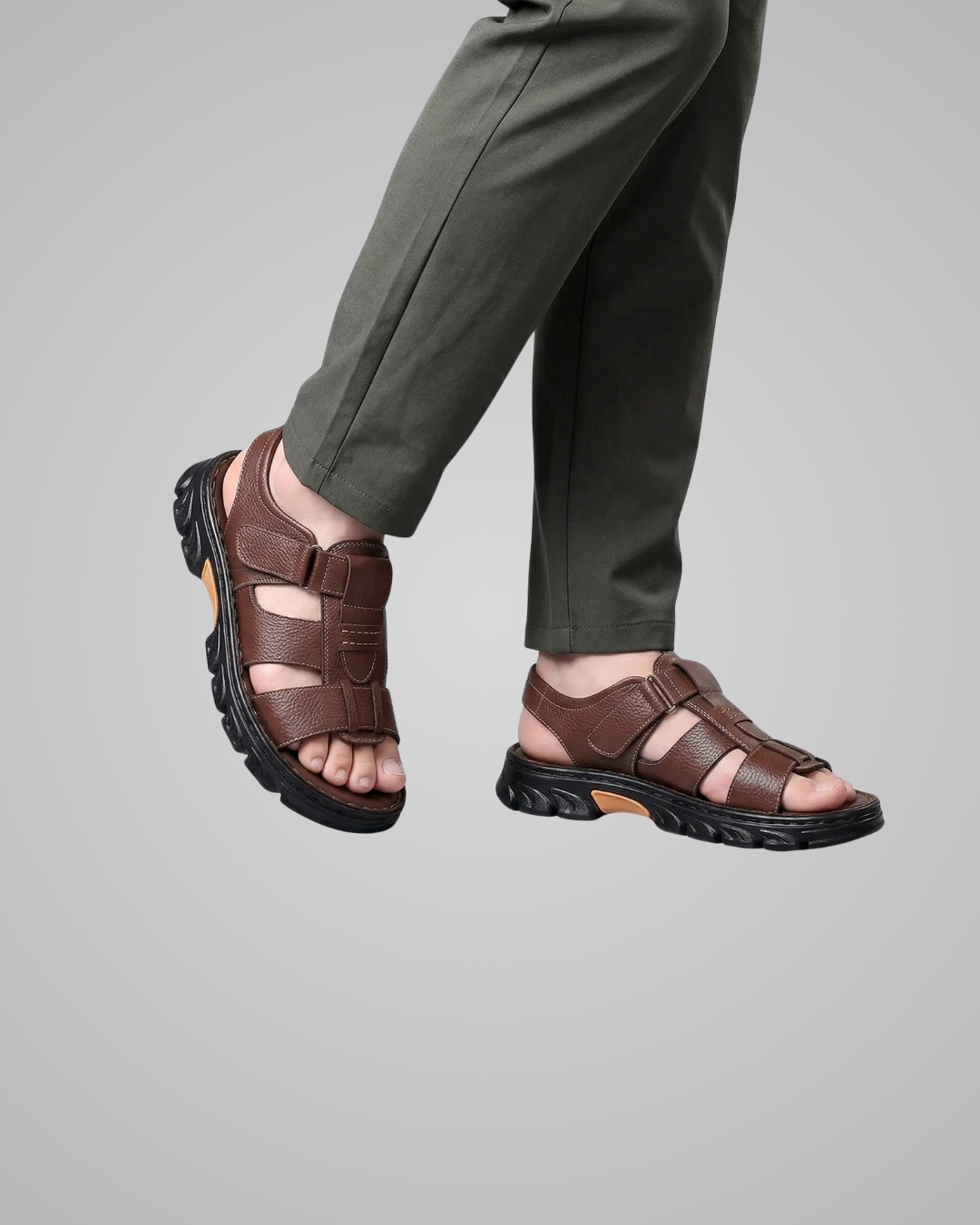 Brown sandals worn with gray pants on a gray background