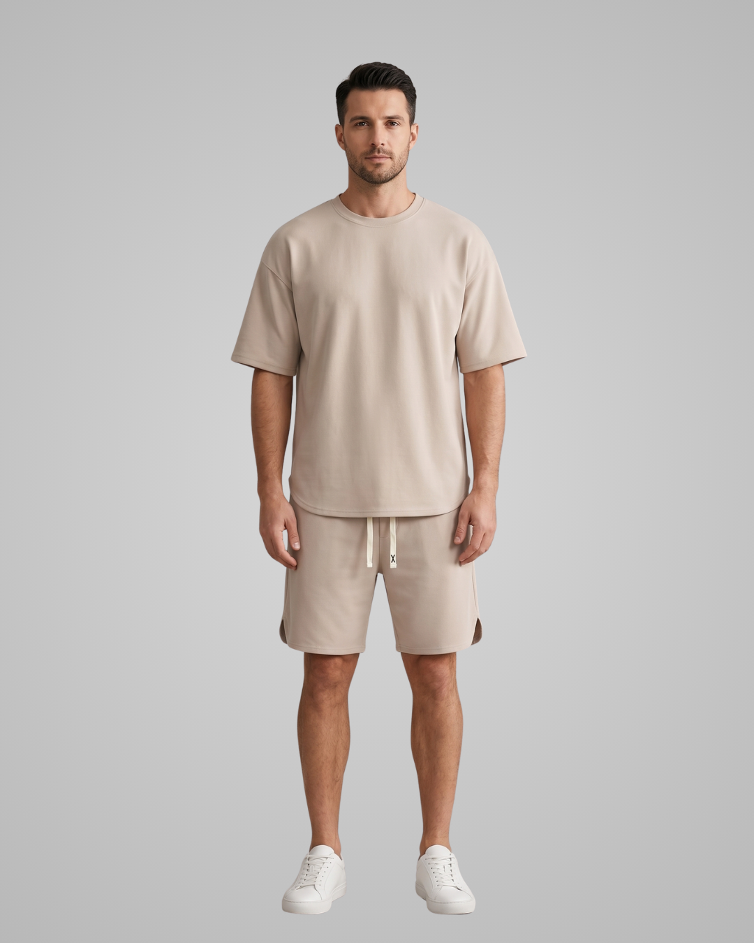 Man wearing a beige outfit with shorts and a t-shirt on a gray background