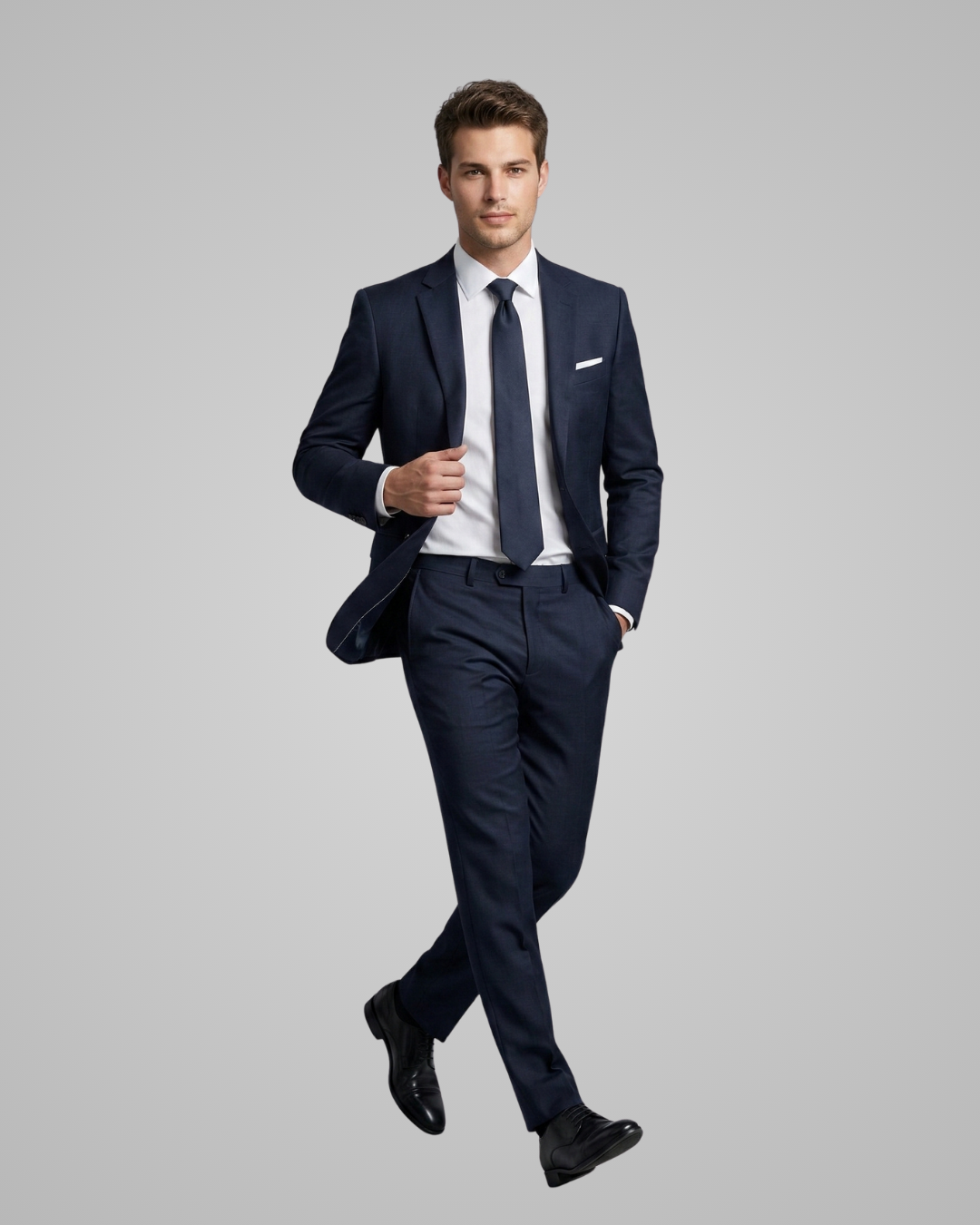 Man wearing a navy suit with a white shirt and black shoes on a gray background