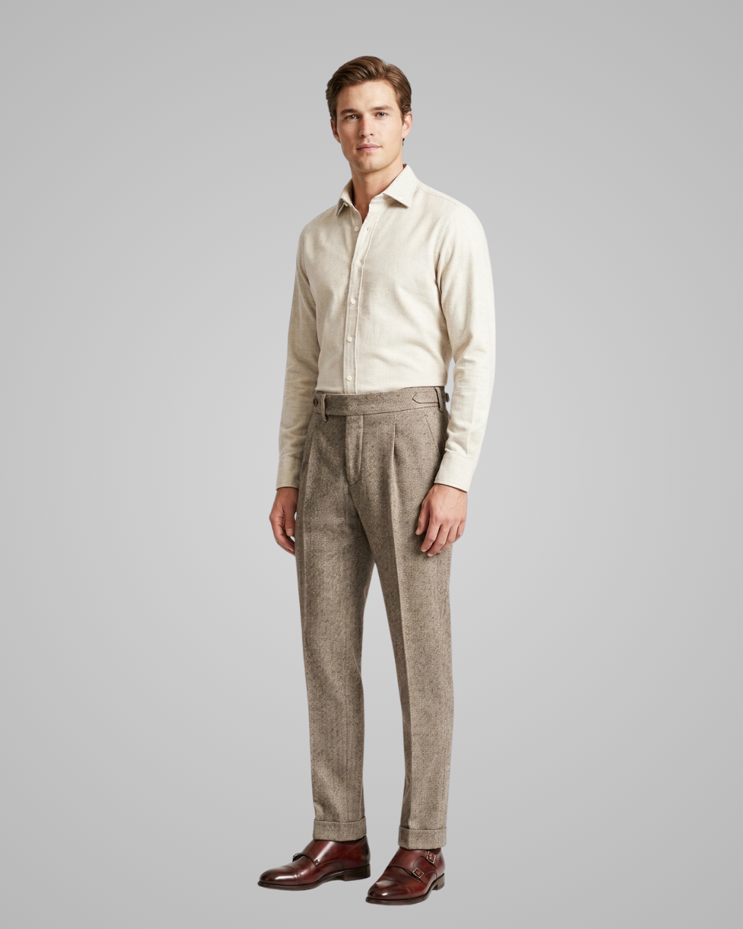 Man wearing a light-colored shirt and patterned pants on a gray background