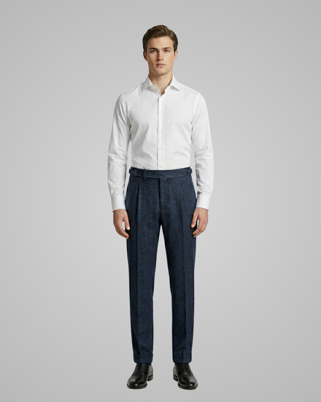 Man wearing a white dress shirt and dark pants on a gray background