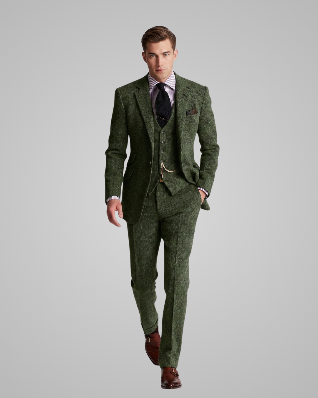 Man wearing a green tweed suit with a white shirt and brown shoes on a gray background
