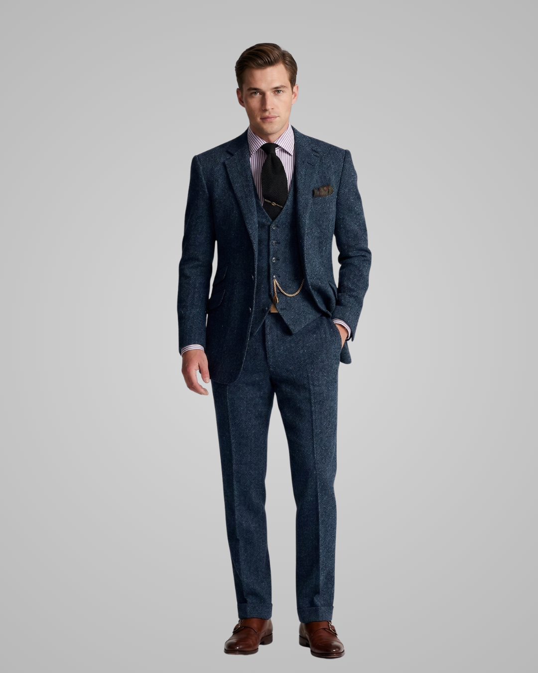 Man wearing a blue suit with a white shirt and brown shoes on a gray background