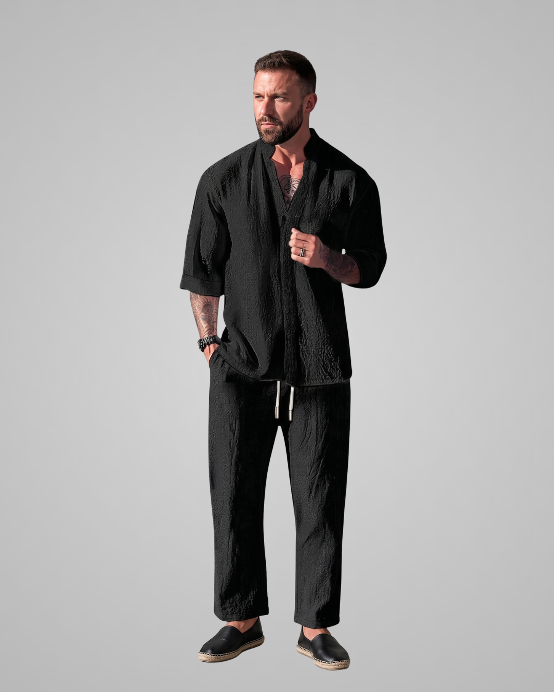 Man wearing a black outfit on a gray background
