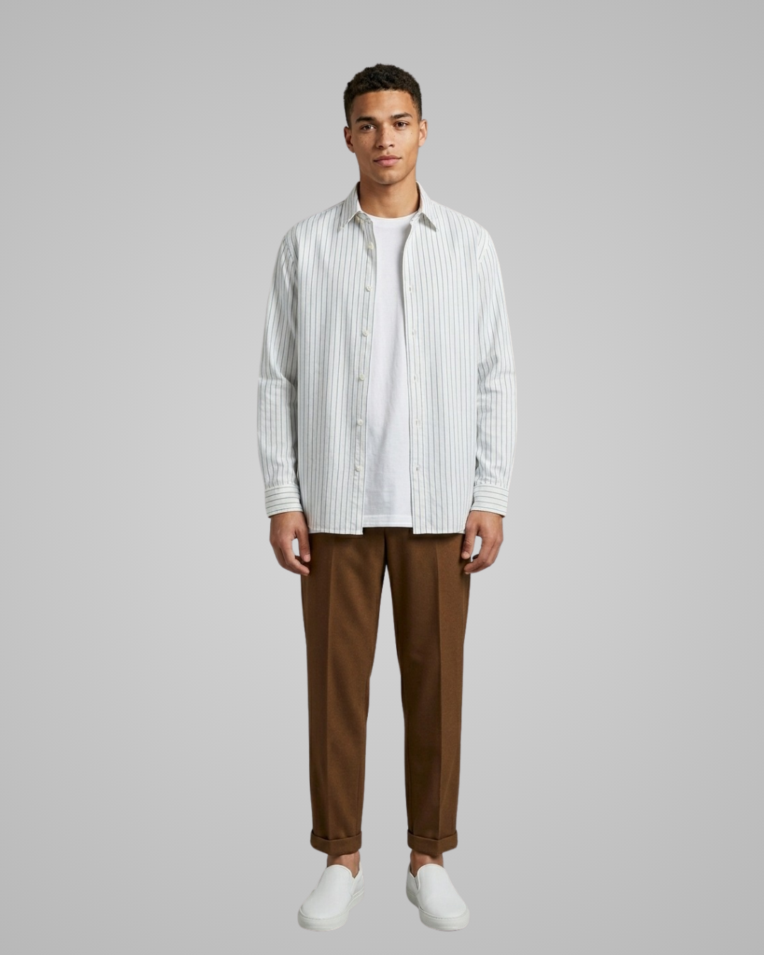 Man wearing a striped shirt and brown pants on a gray background