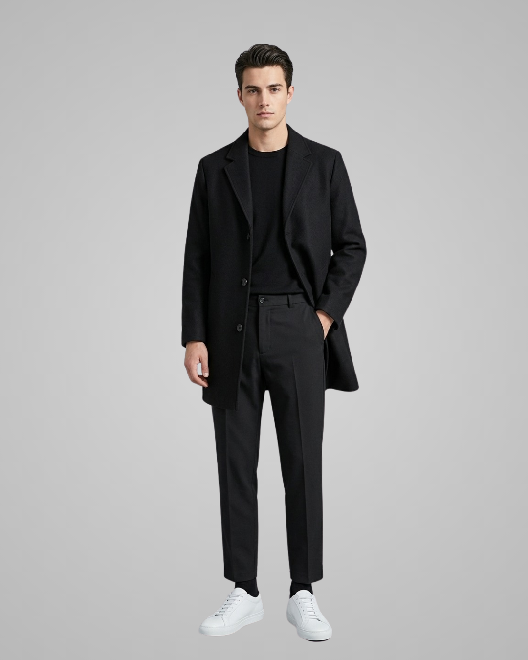 Man wearing a black suit with white sneakers on a gray background