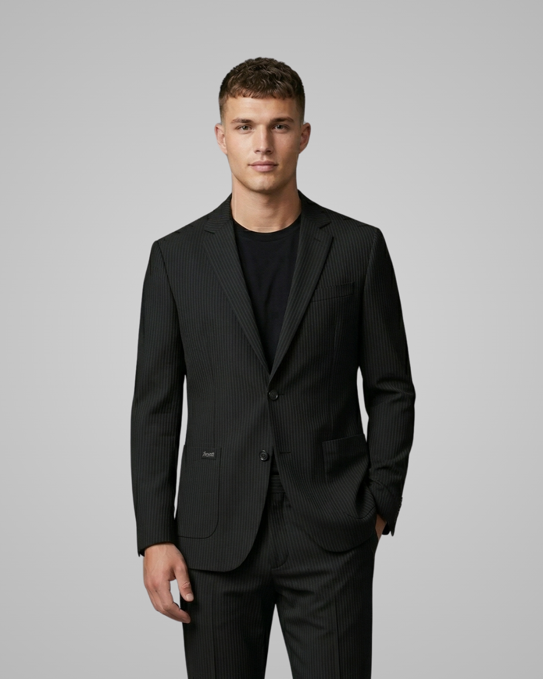 Man wearing a black suit against a gray background