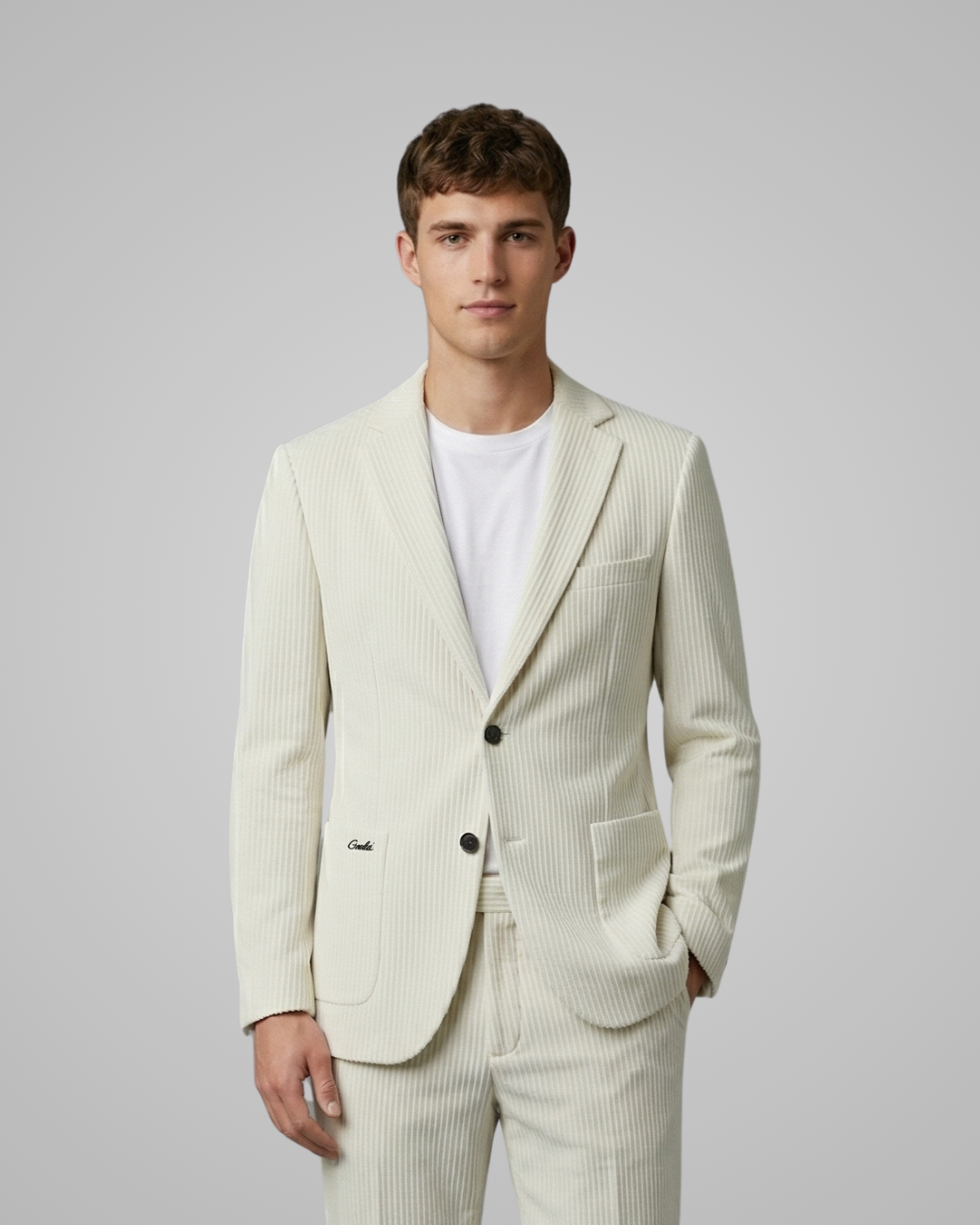 Man wearing a light-colored suit with a white shirt on a plain background