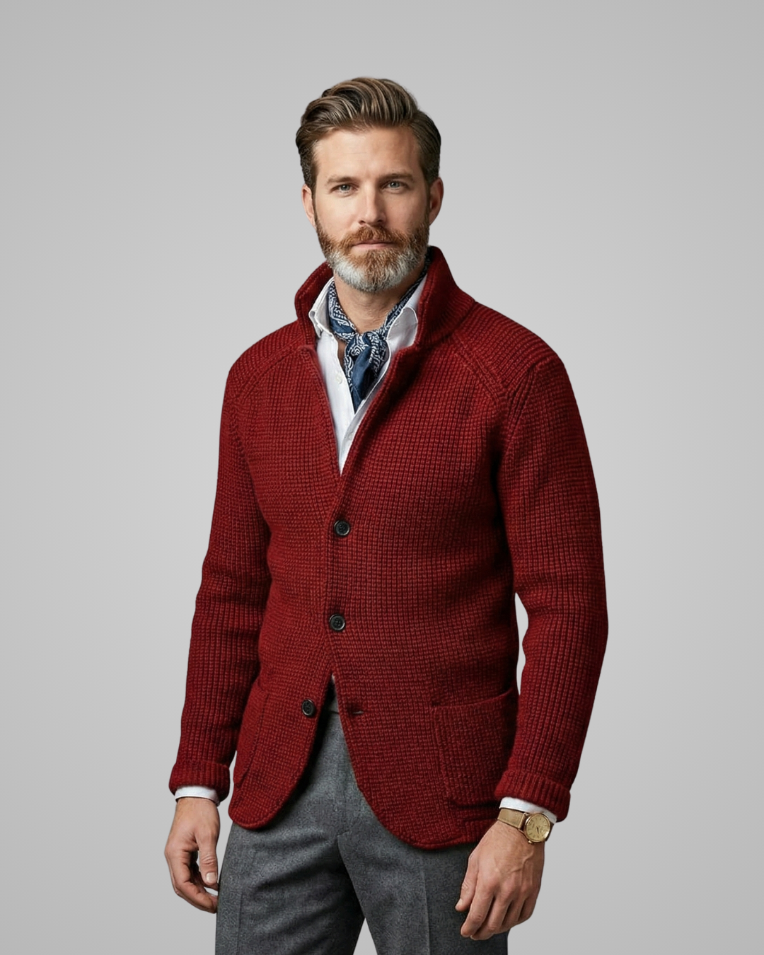 Man wearing a red knitted cardigan over a patterned shirt with a gray background