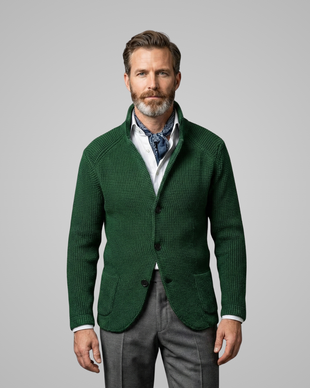 Man wearing a green blazer over a patterned shirt on a gray background