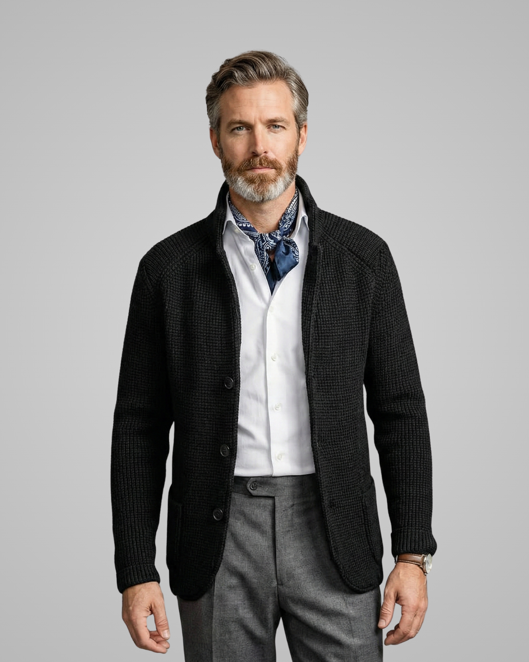 Man wearing a black jacket, white shirt, and gray pants on a gray background