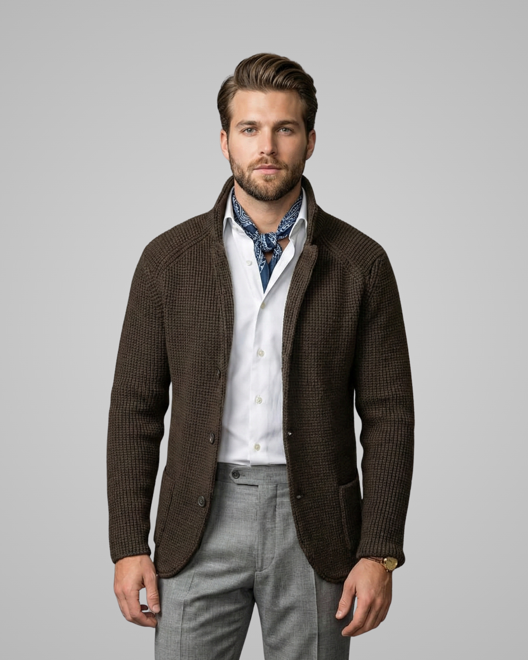 Man wearing a brown blazer over a white shirt with a patterned tie on a gray background