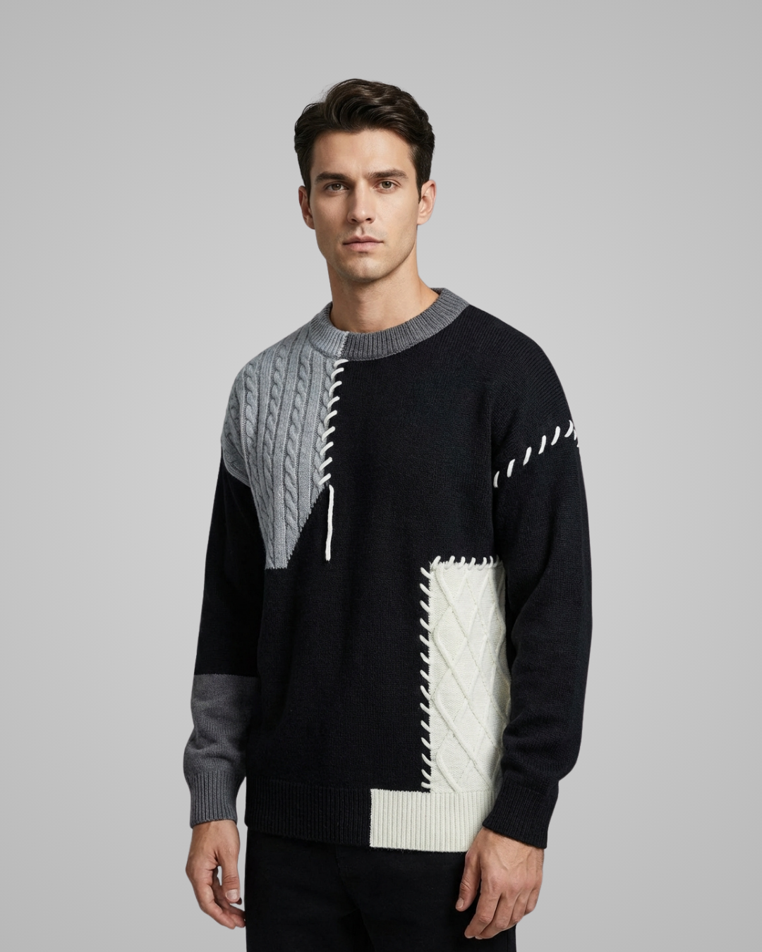 Man wearing a black sweater with geometric patterns on a gray background