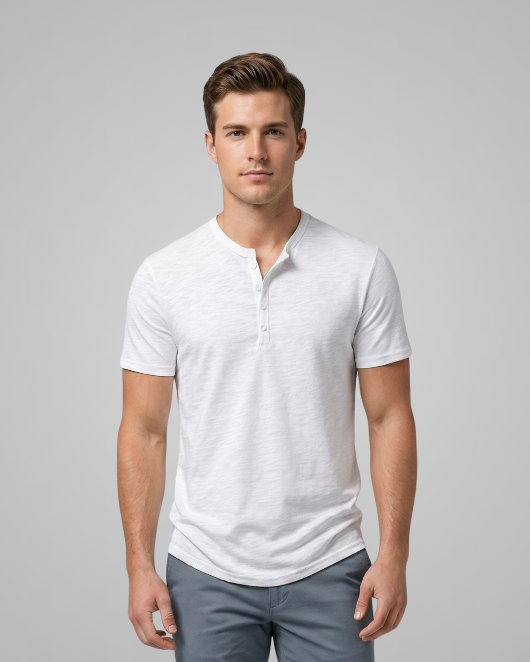 Man wearing a white henley shirt and gray pants on a gray background