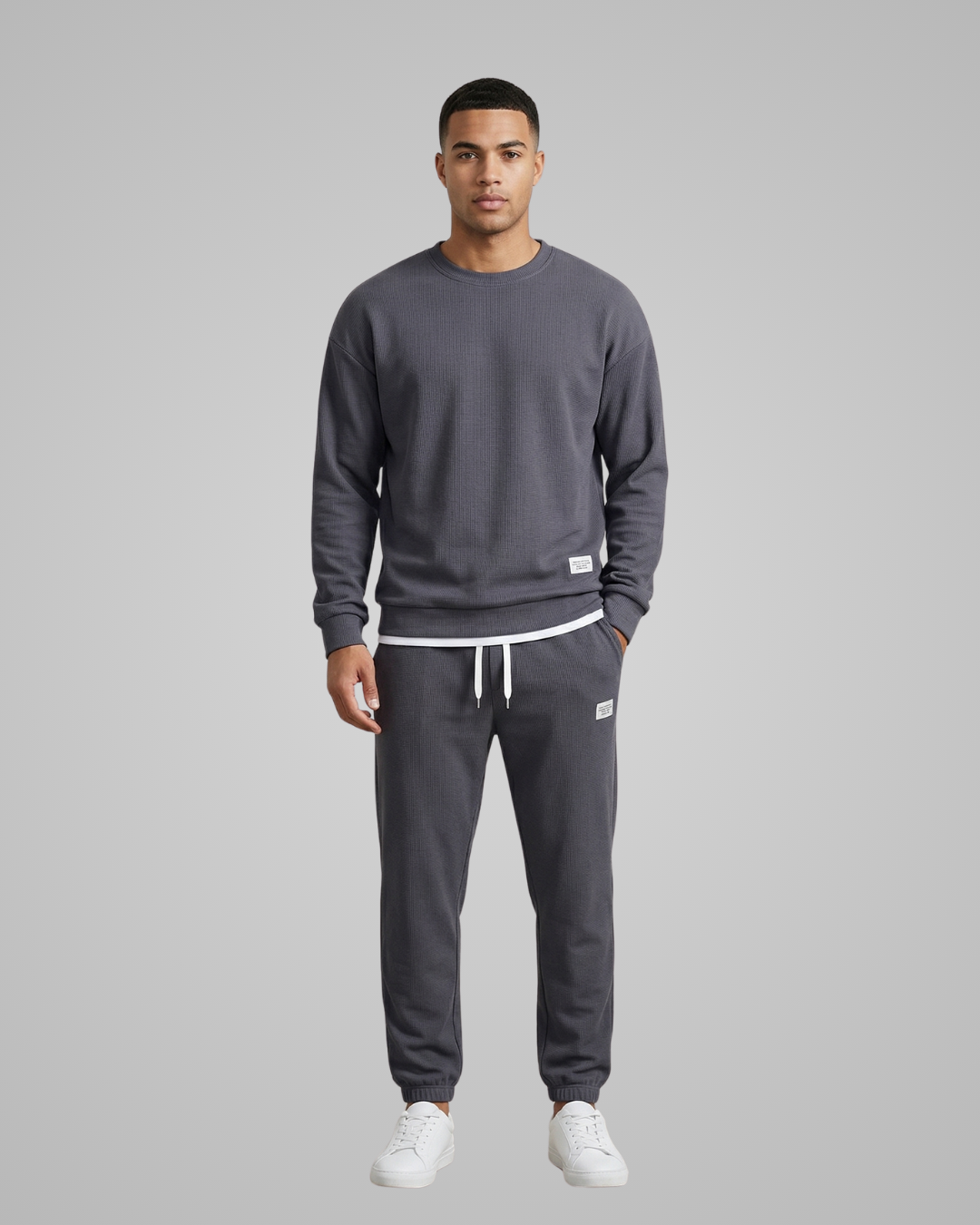 Man wearing a gray sweatshirt and pants set on a gray background