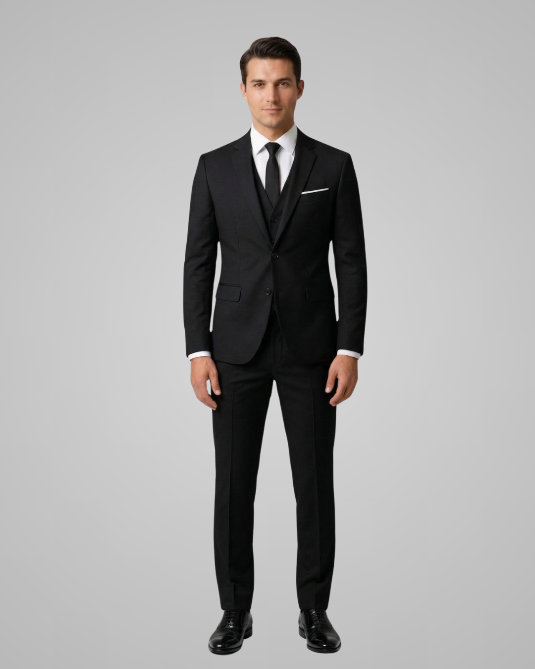 Man wearing a black suit with a white shirt and tie on a gray background