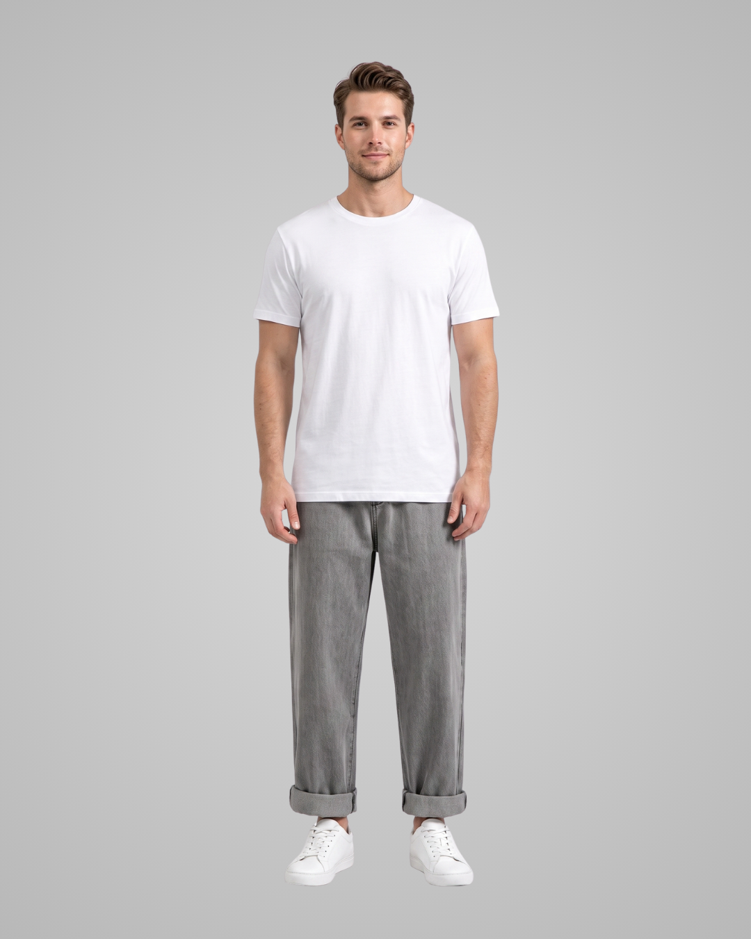 Man wearing a plain white t-shirt and gray pants on a gray background