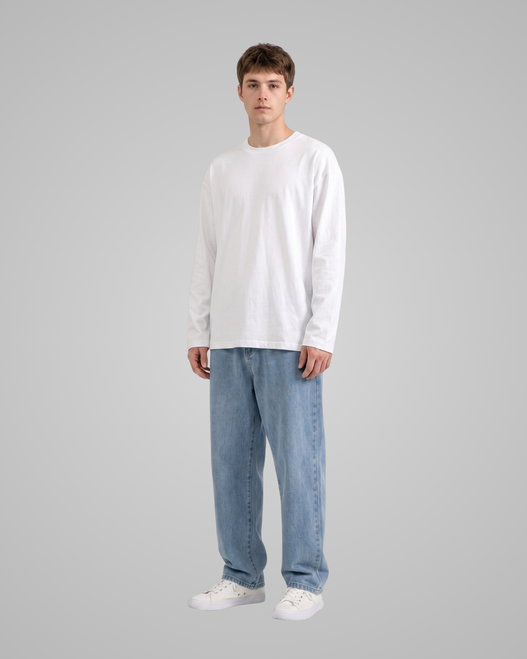 Person wearing a white long-sleeve shirt and blue jeans on a gray background