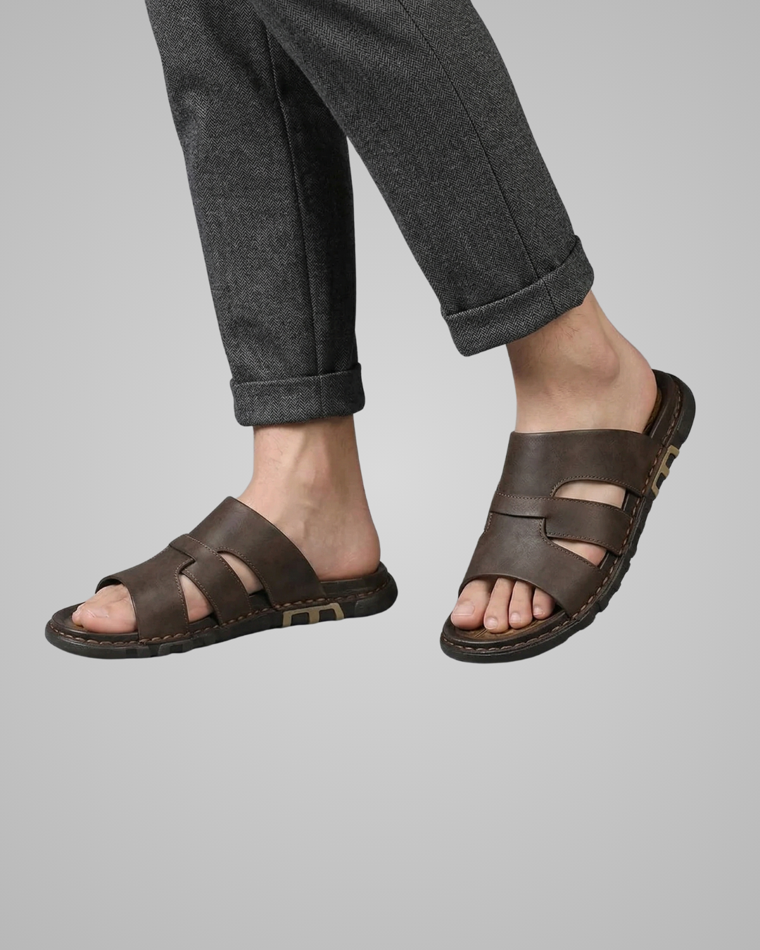 Brown sandals worn with gray pants on a light gray background
