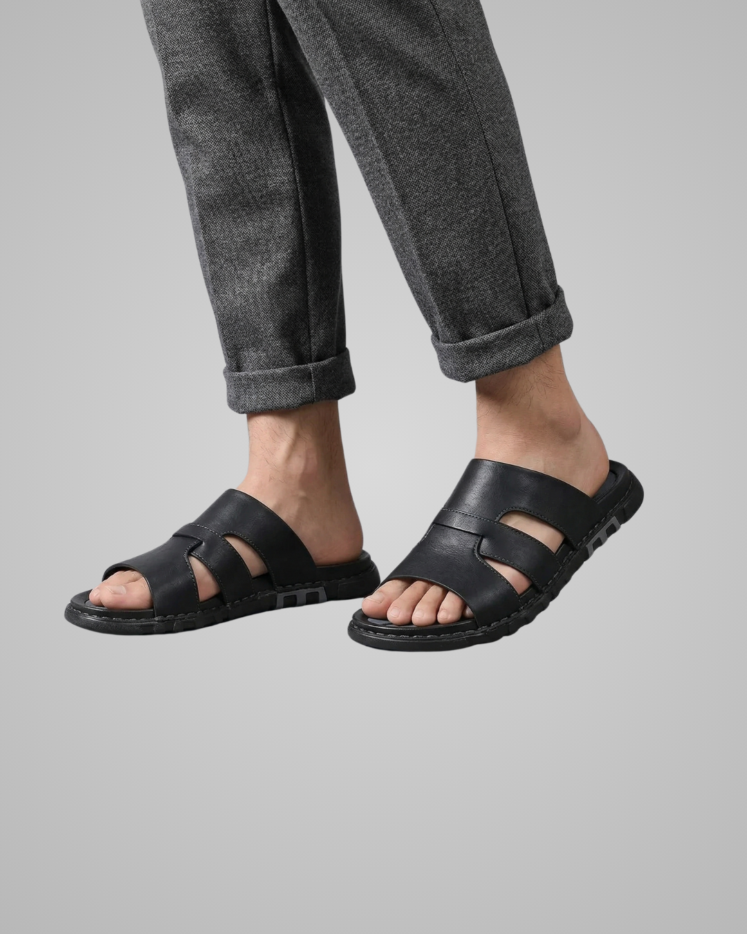 Person wearing black sandals on a gray background