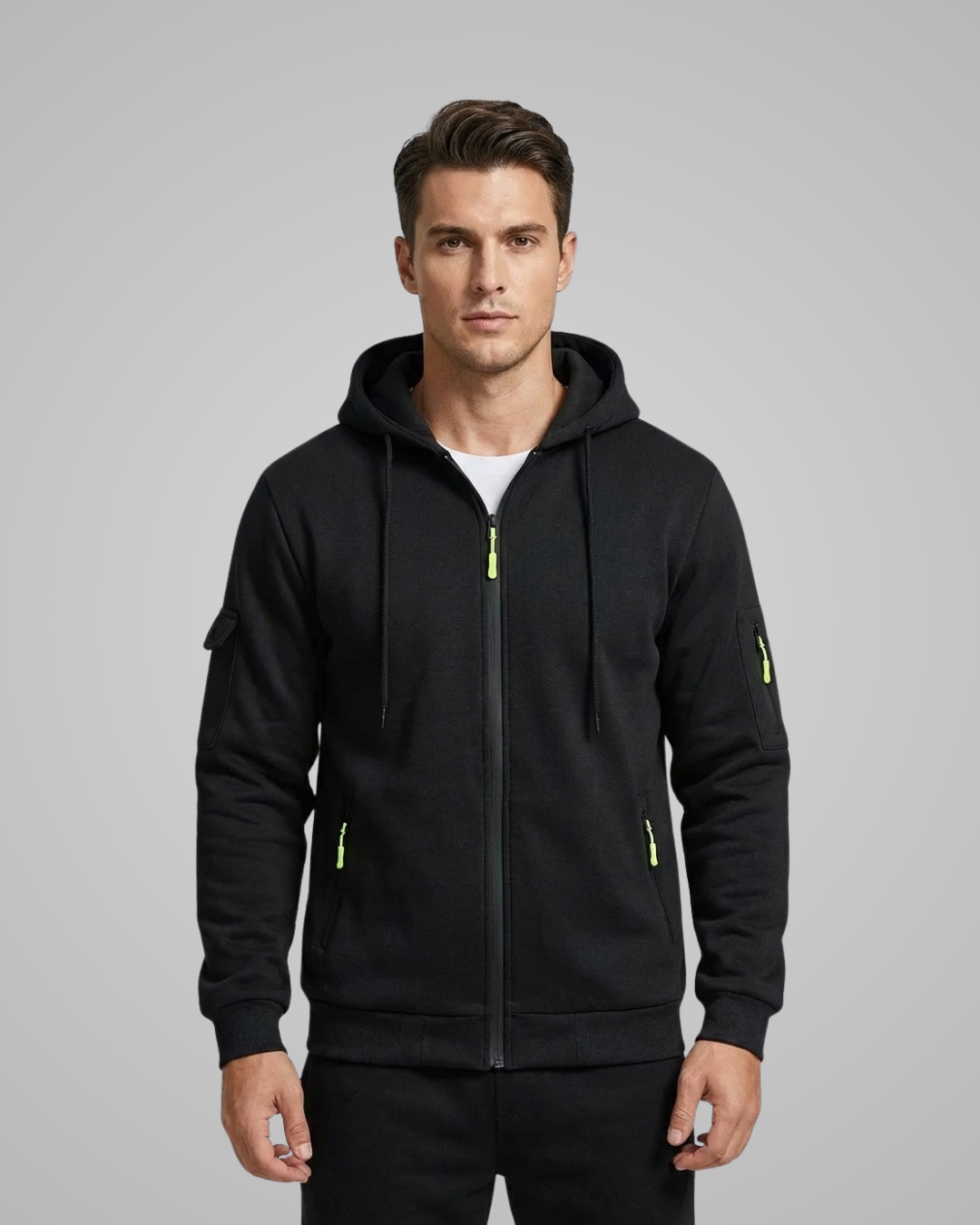Man wearing a black hoodie with yellow zippers on a gray background