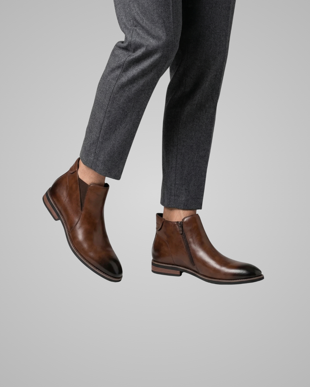Brown leather boots worn with gray pants on a light gray background