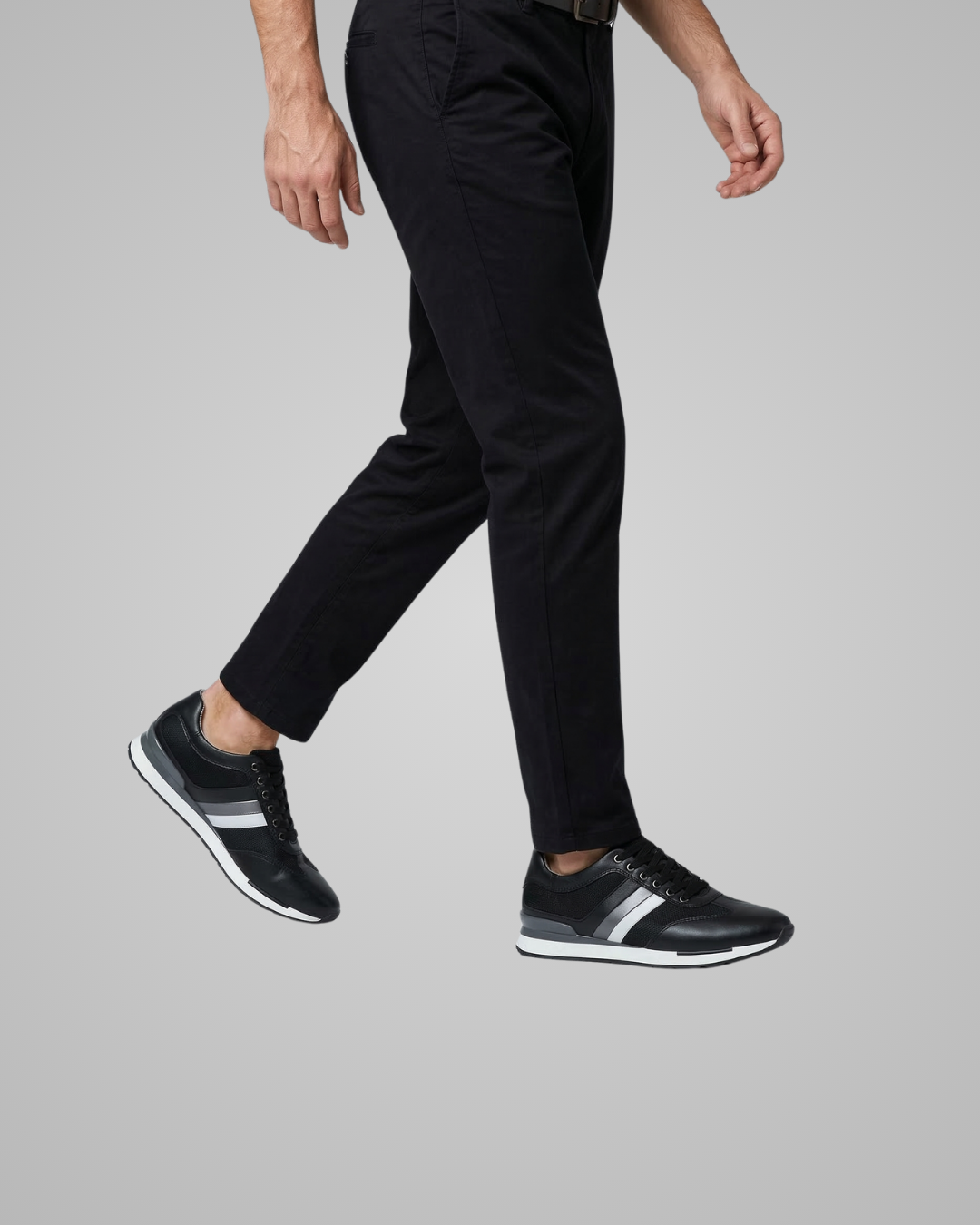 Person wearing black dress pants and black shoes on a gray background