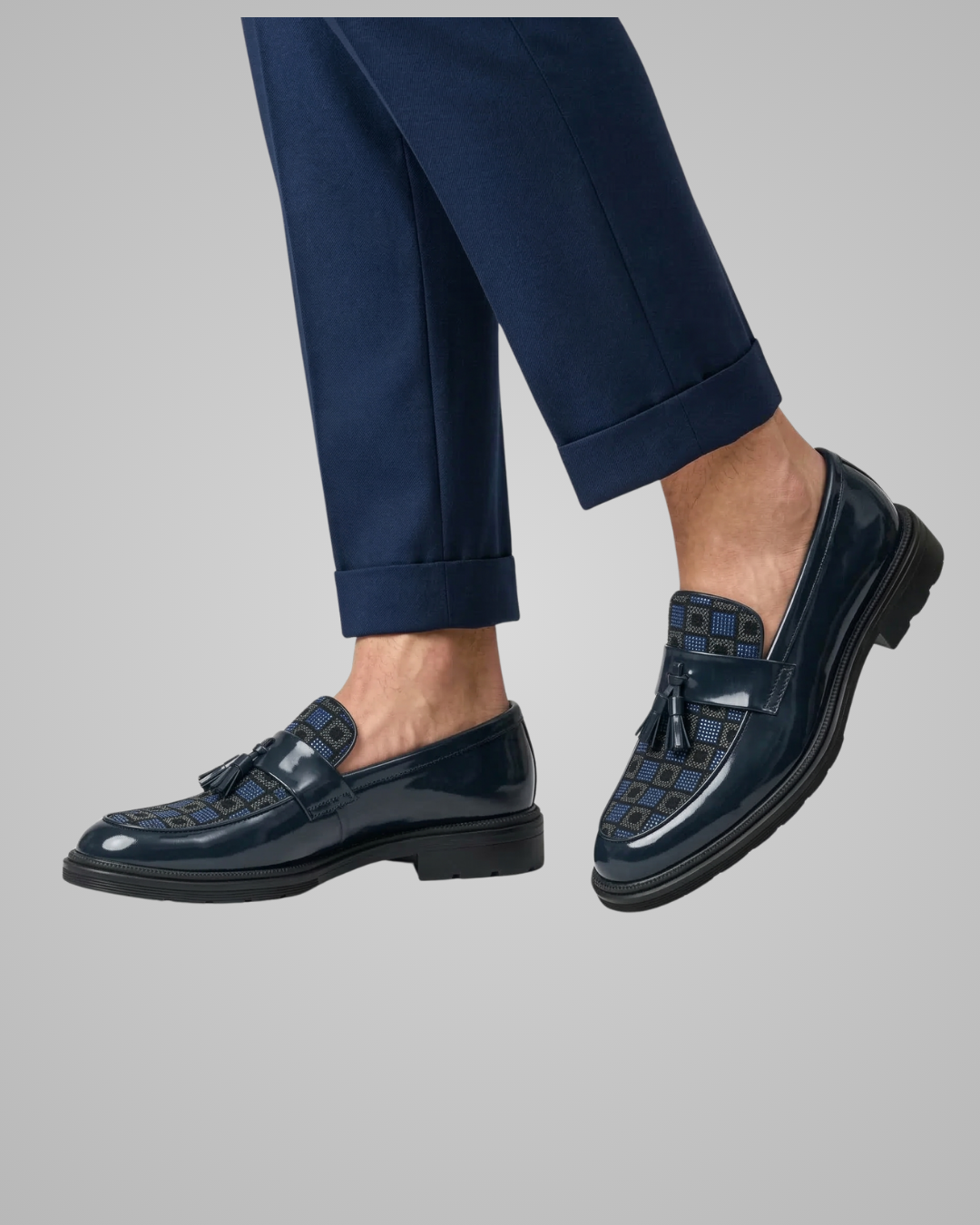 Navy loafers worn with navy pants on a gray background