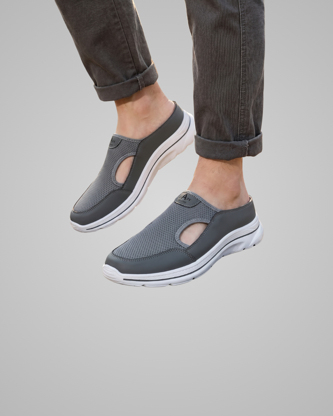 Gray slip-on shoes worn with rolled-up jeans on a gray background