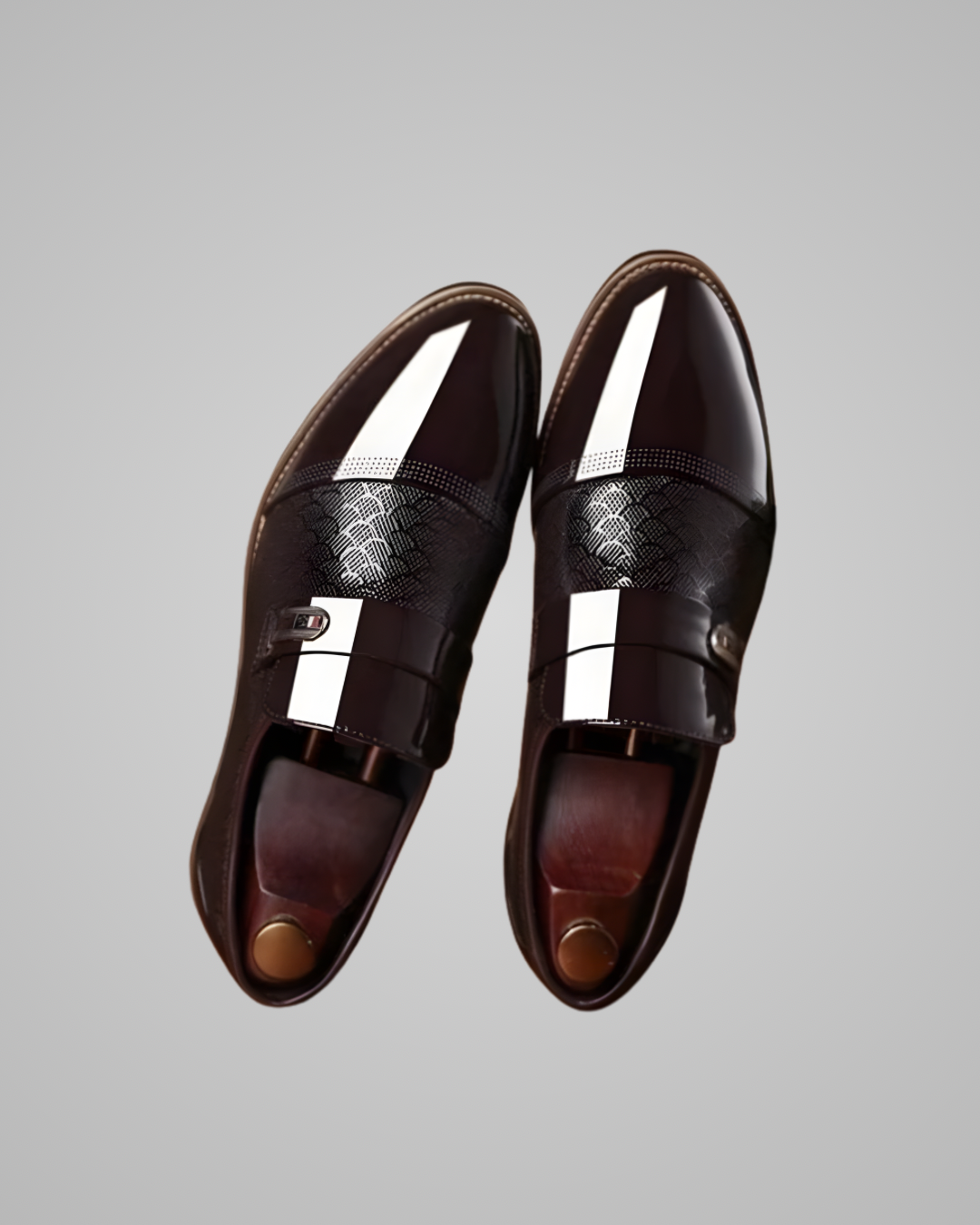 Pair of brown leather shoes with metallic accents on a gray background