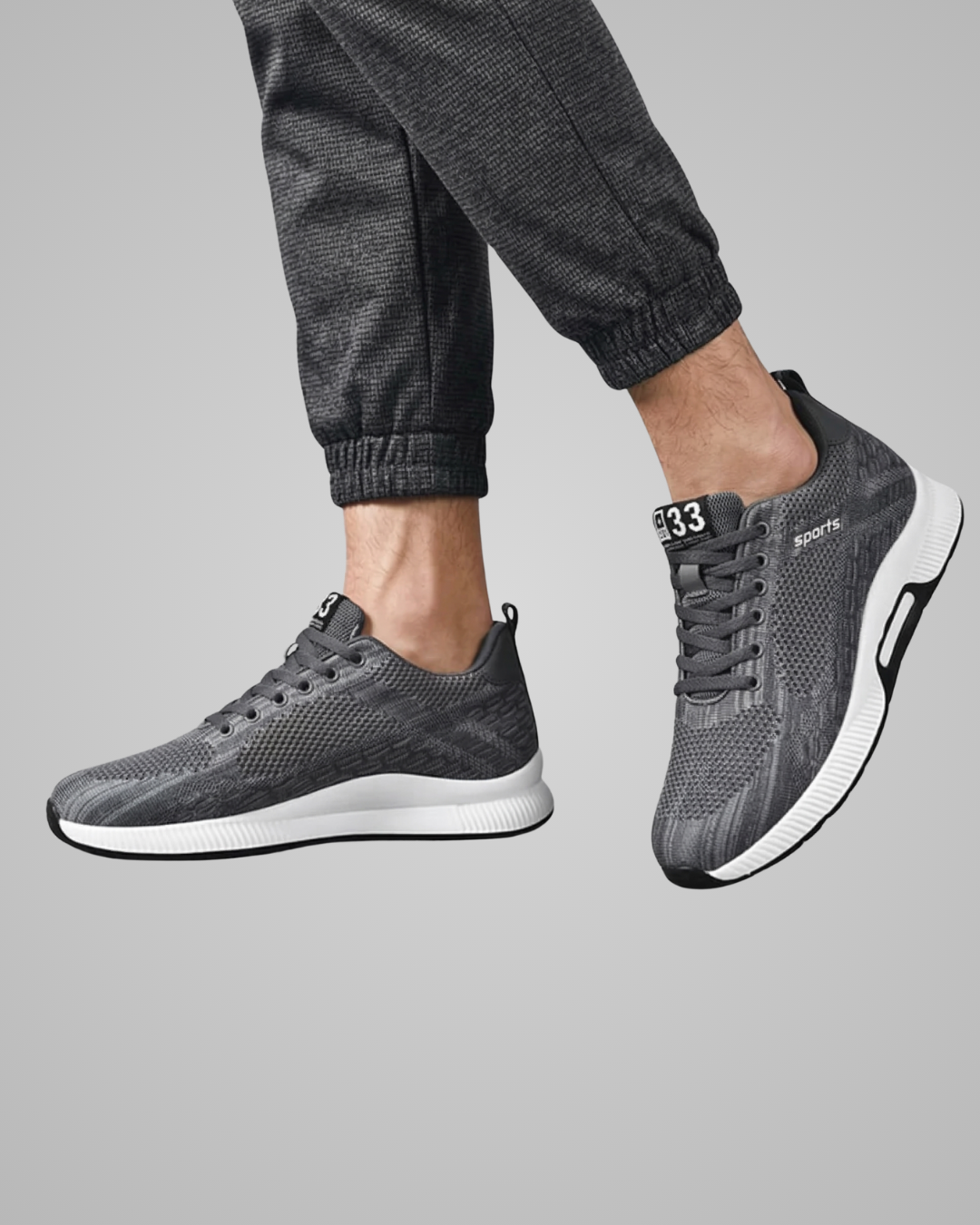 Gray athletic shoes worn with dark gray pants on a light gray background