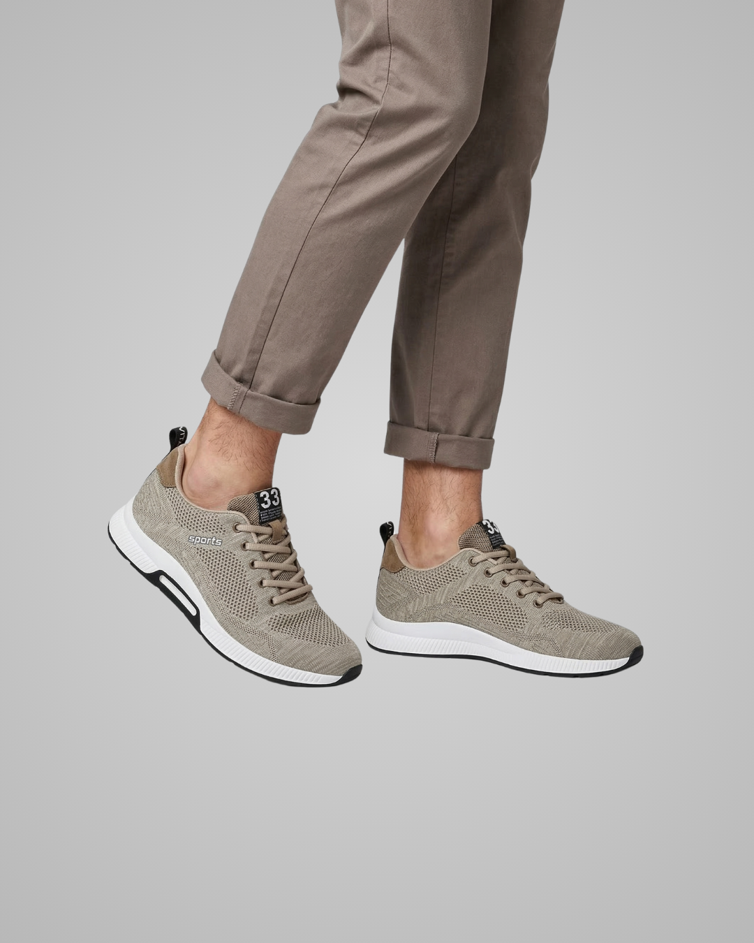 Person wearing beige sneakers and brown pants on a gray background