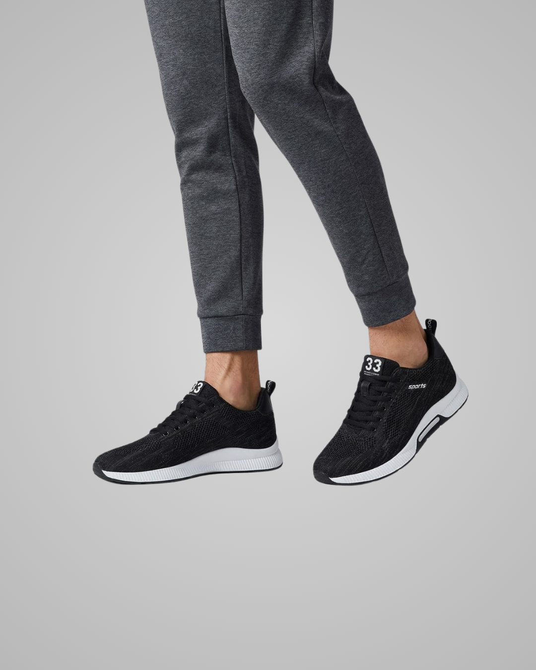 Black sneakers worn with gray sweatpants on a light gray background