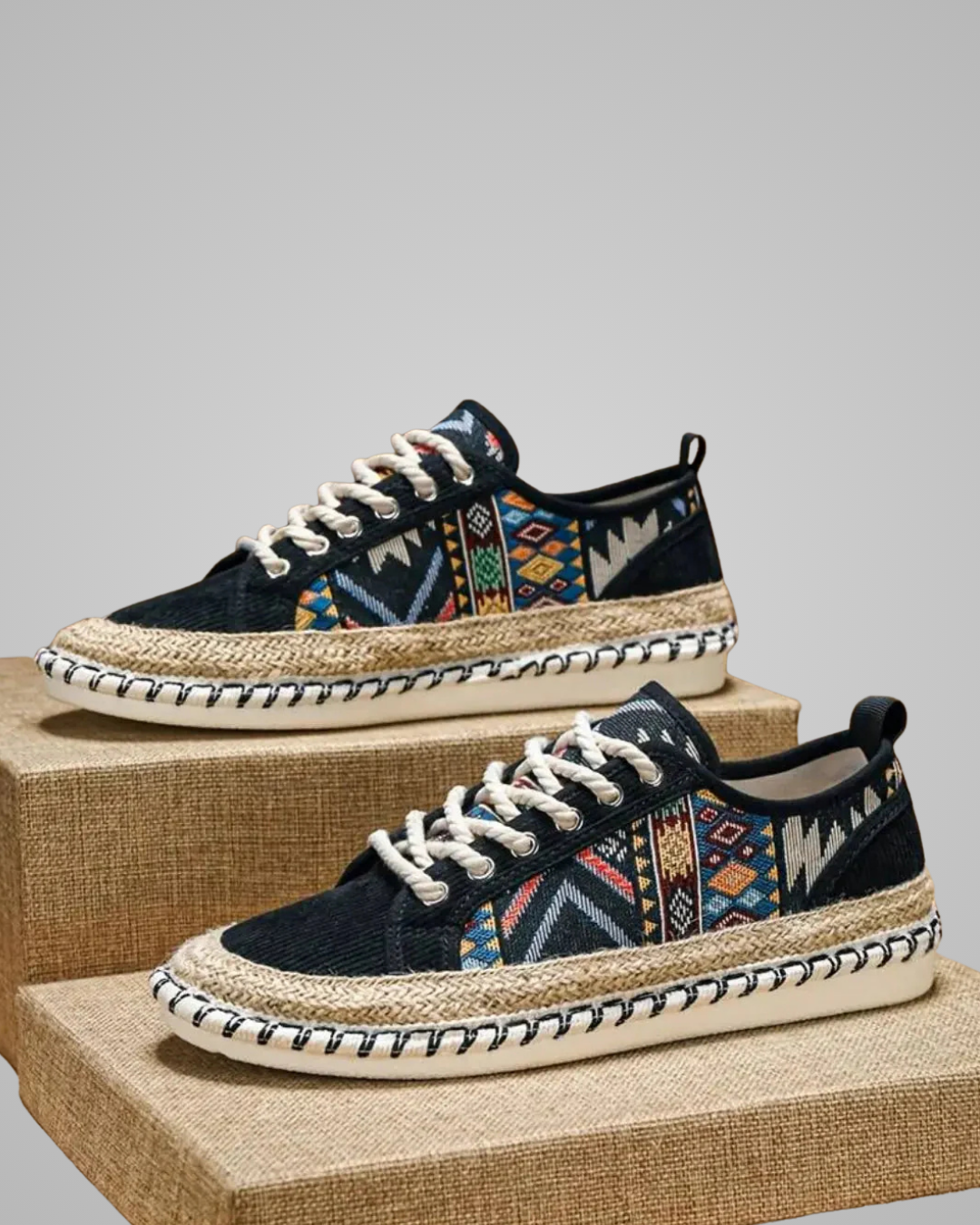 Pair of black sneakers with colorful pattern on a gray background