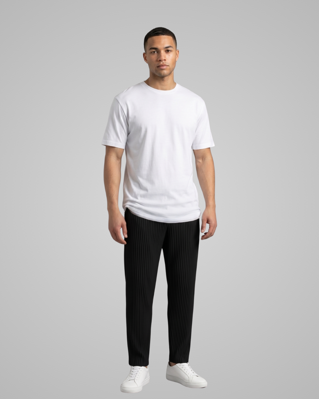 Man wearing a white t-shirt and black pants on a gray background