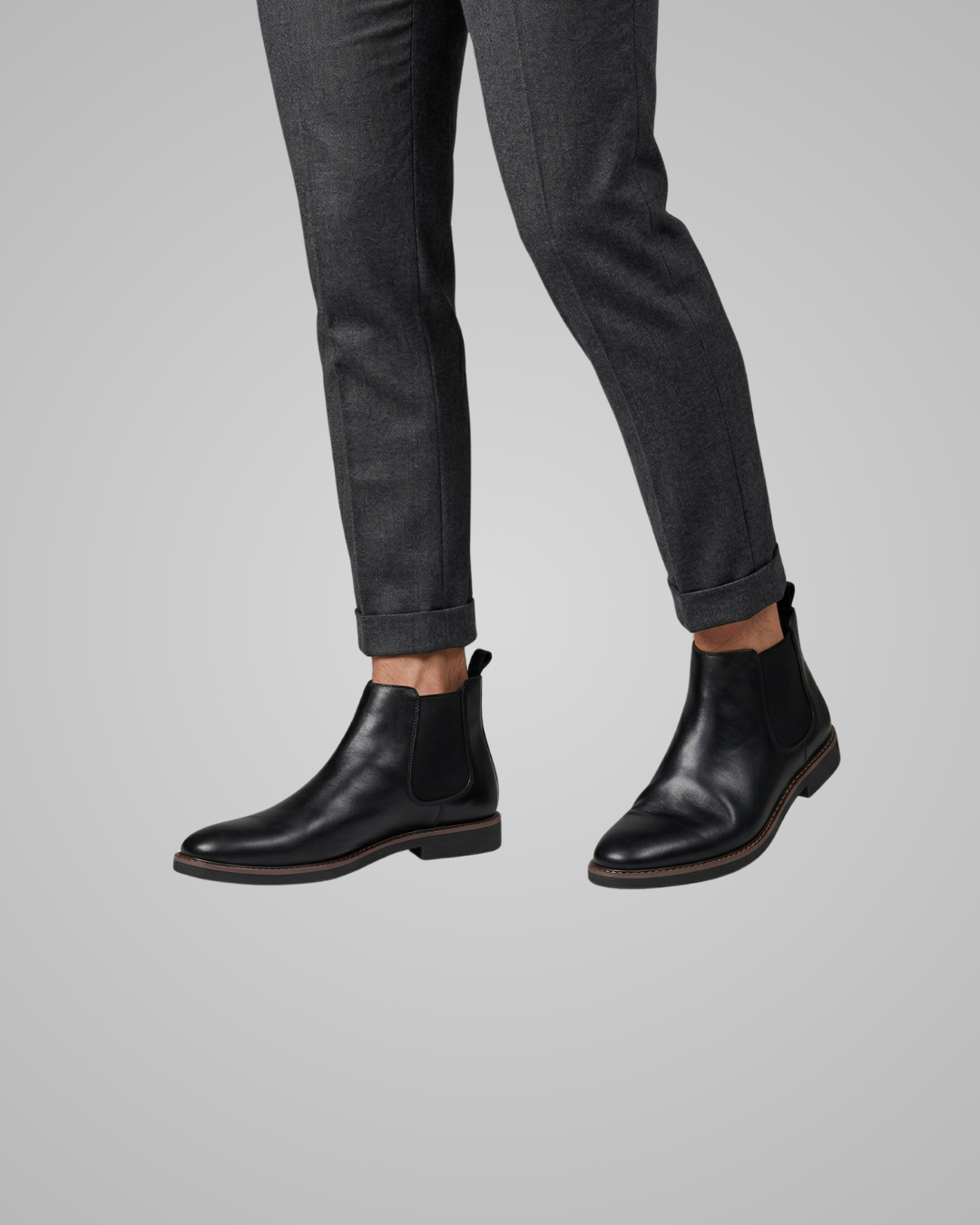 Black leather boots worn with gray pants on a light gray background