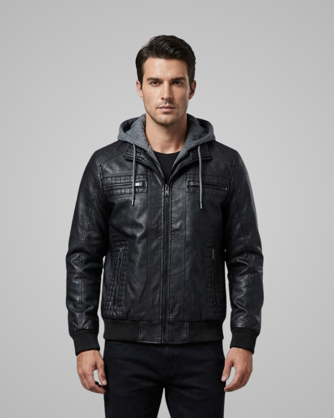 Man wearing a black leather jacket with a gray hood on a gray background