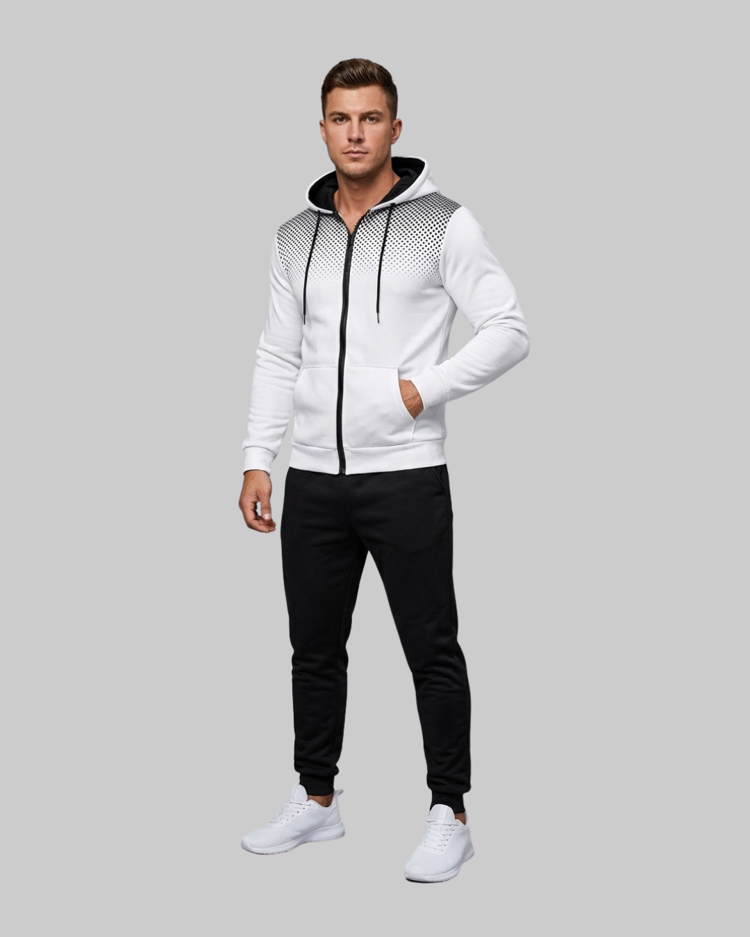 A man modeling a white zip-up hoodie with black mesh patterned shoulder panels, black drawstrings, and a black hood lining, paired with black jogger pants and white sneakers, against a solid gray background.