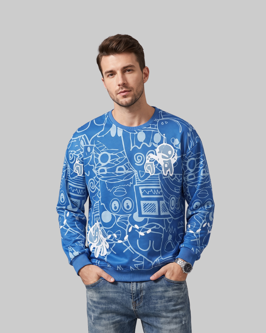 A man wearing a blue crewneck sweatshirt with a white graphic print of astronauts and space-themed doodles, paired with blue jeans, against a solid gray background.