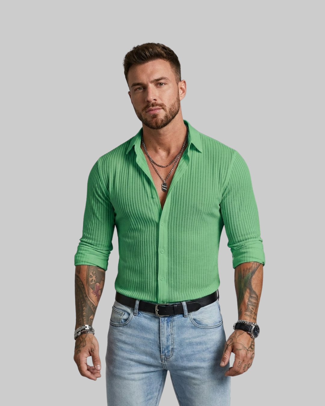 A man modeling a bright green ribbed long-sleeve button-up shirt with light blue jeans, standing against a solid gray background.