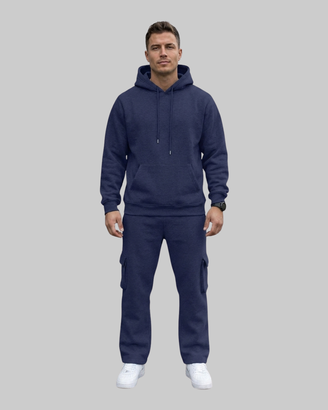 A man modeling a matching navy blue hoodie and cargo sweatpants set against a solid gray background.