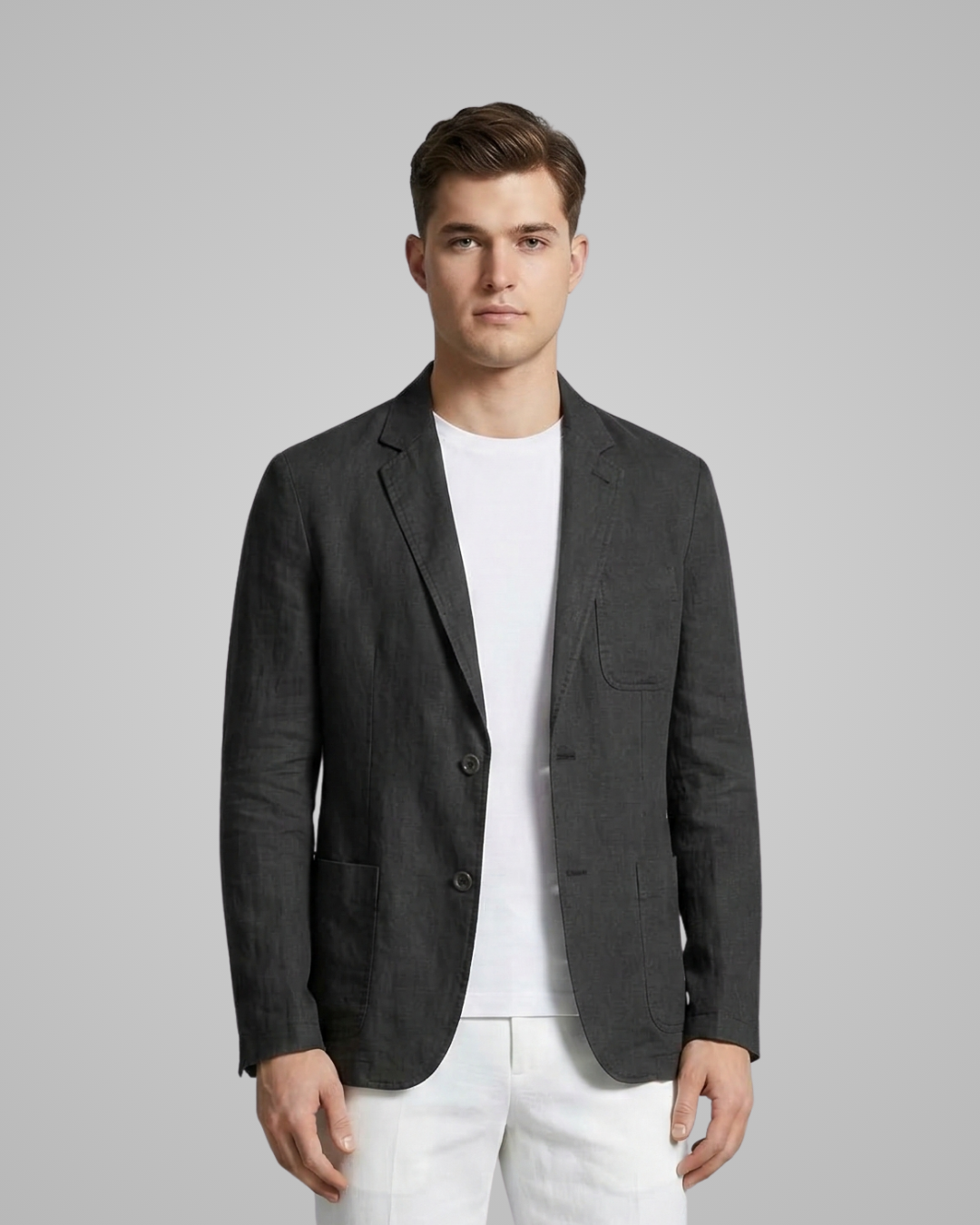 Man wearing a dark gray blazer over a white shirt on a light gray background