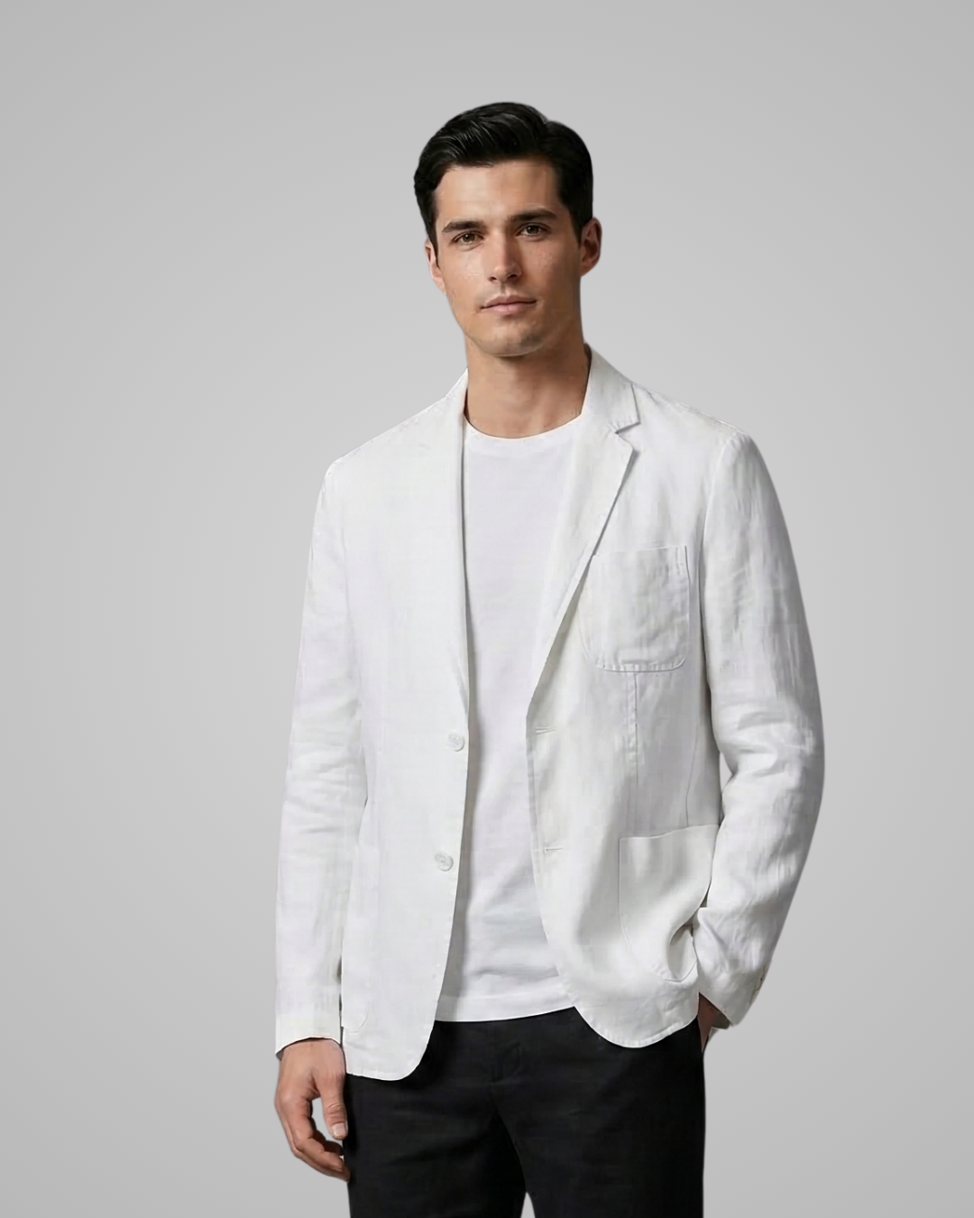 Man wearing a white blazer over a white shirt with black pants on a gray background