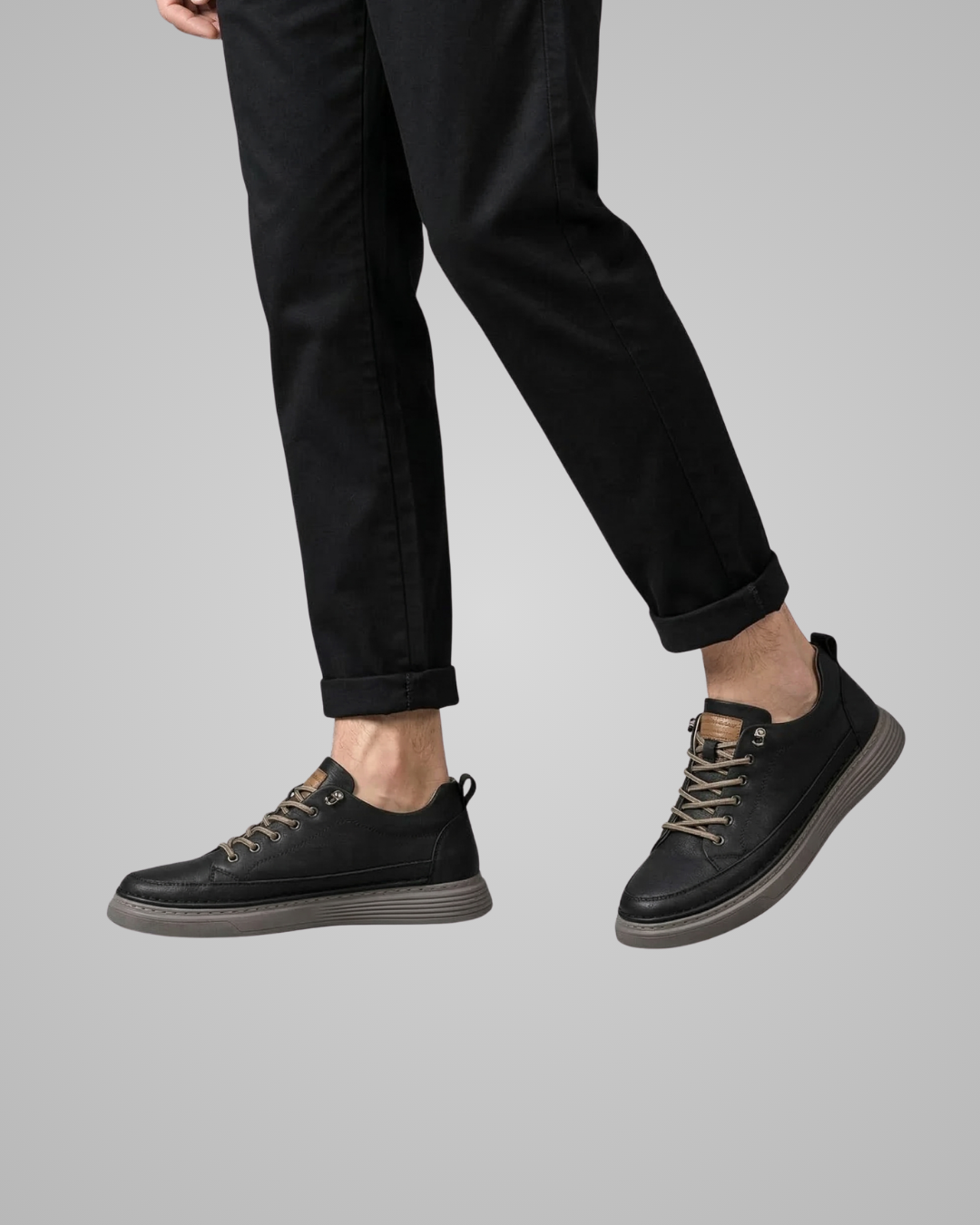 Person wearing black leather shoes and black pants on a gray background