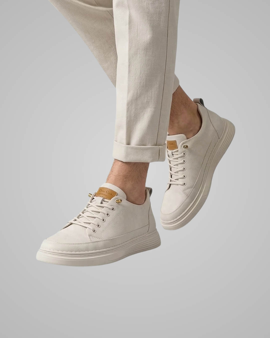 White sneakers worn with beige pants on a light gray background